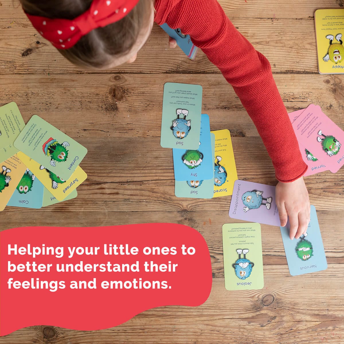 Child playing with emotion cards on a wooden table, with text about understanding feelings.
