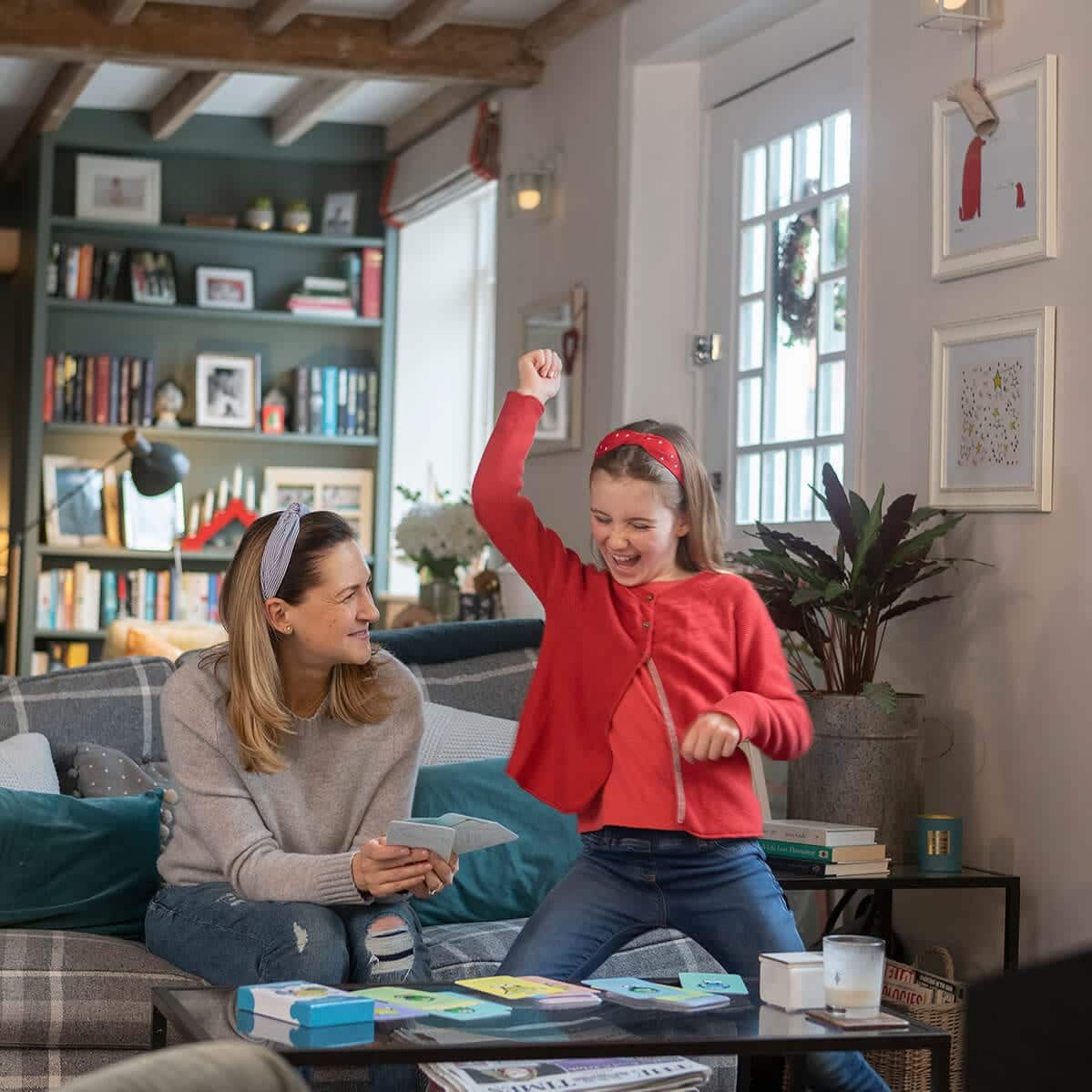 Woman and child playing a board game in a cozy living room.